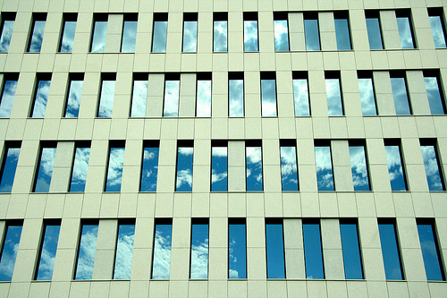 Afbeelding van een kantoorgebouw met een weerspiegeling van de lucht in de ramen